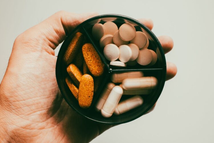 Hand met verschillende voedingssupplementen